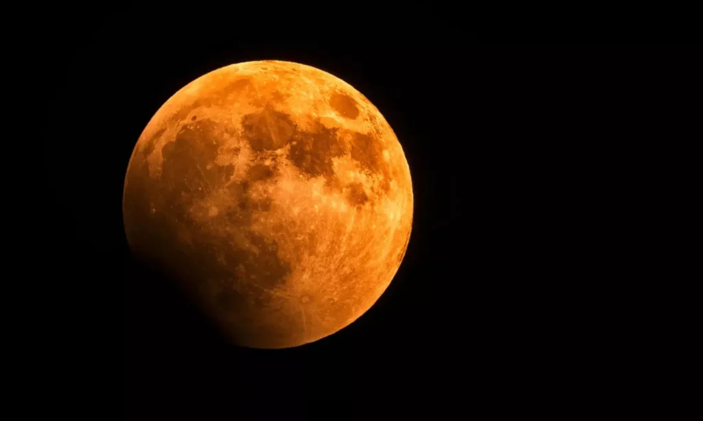 Close-up view of a solar eclipse 2025 with the moon partially covering the sun, showing a bright orange-red crescent.