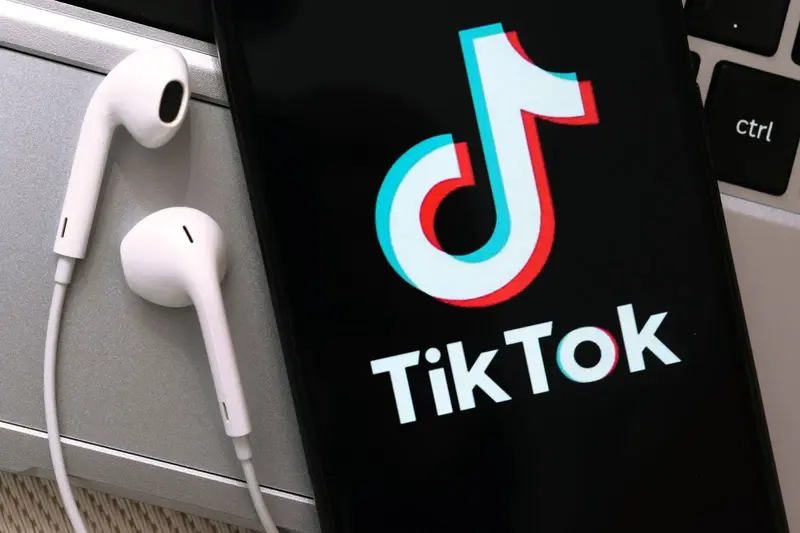 Smartphone displaying the TikTok logo on a laptop keyboard, highlighting the TikTok Sale.