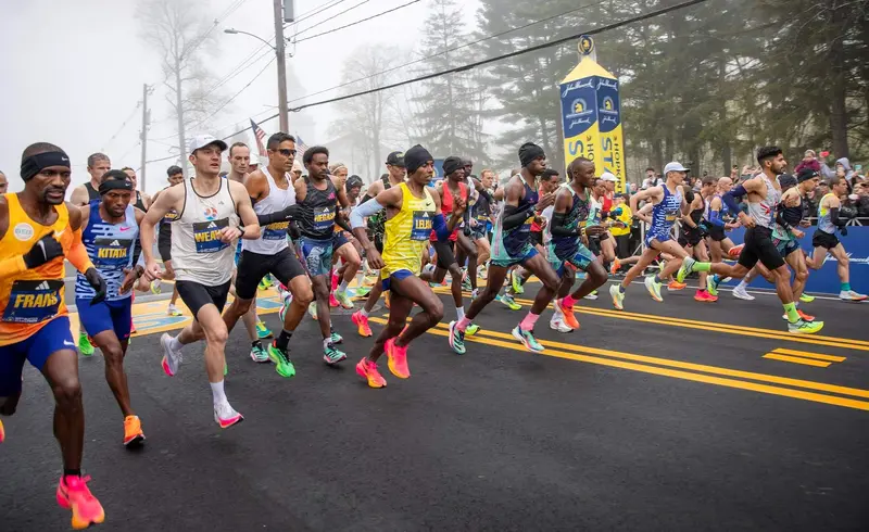 Elite runners start Boston Marathon 2025 on foggy road.