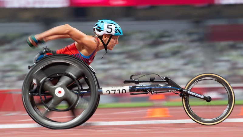 Boston Marathon 2025 wheelchair athlete racing on track, blue helmet, high speed