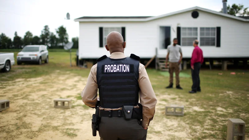 What is probation: officer in vest conducts home visit for community supervision.
