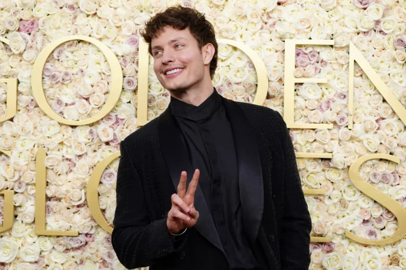 Matt Rife: peace sign, black suit, Golden Globes floral backdrop.