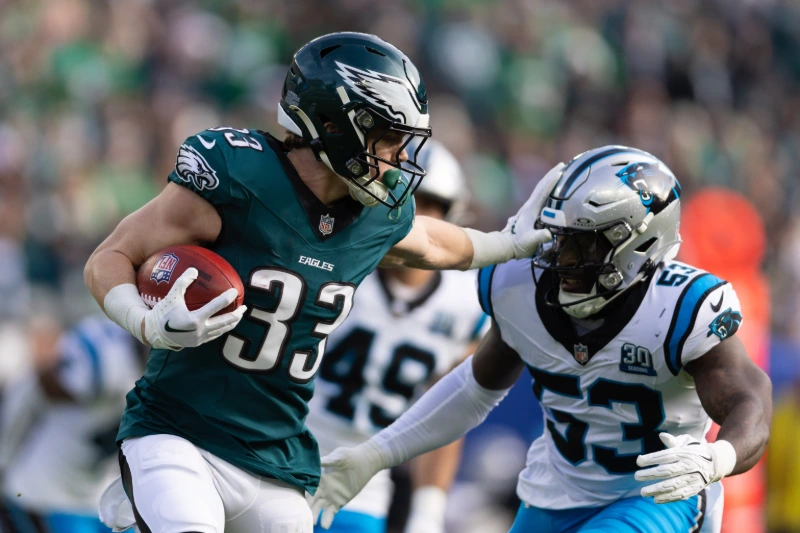 Eagles #33 holds football and stiff-arms Giants defender during intense NFL game, Bill Streicher-Imagn Images.