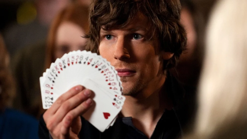 Jesse Eisenberg as magician Daniel Atlas, holding playing cards, from Now You See Me, Image Credits: (Barry Wetcher, SMPSP)