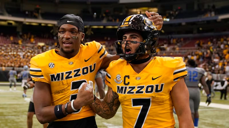 Mizzou football captain and teammate celebrate in gold uniforms, AP Photo/Jeff Roberson.