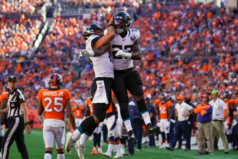Jaguars players leap and celebrate touchdown vs Broncos, NFL Week 7, Jack Dempsey.