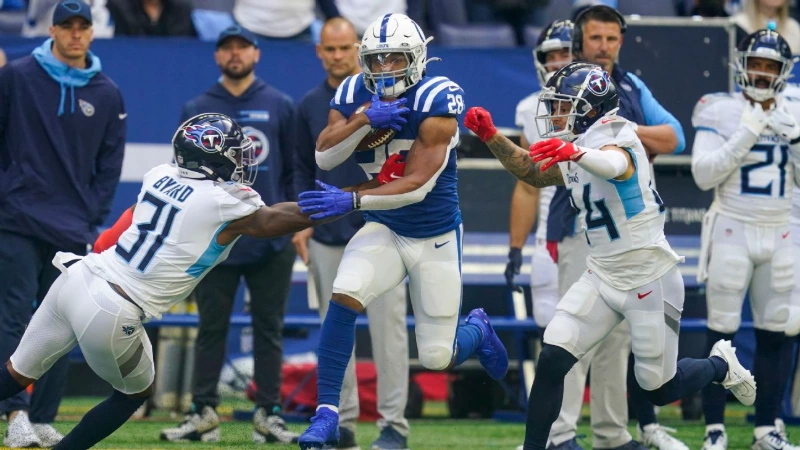 Colts running back dodges Titans defenders along sideline, NFL Week 7 action.