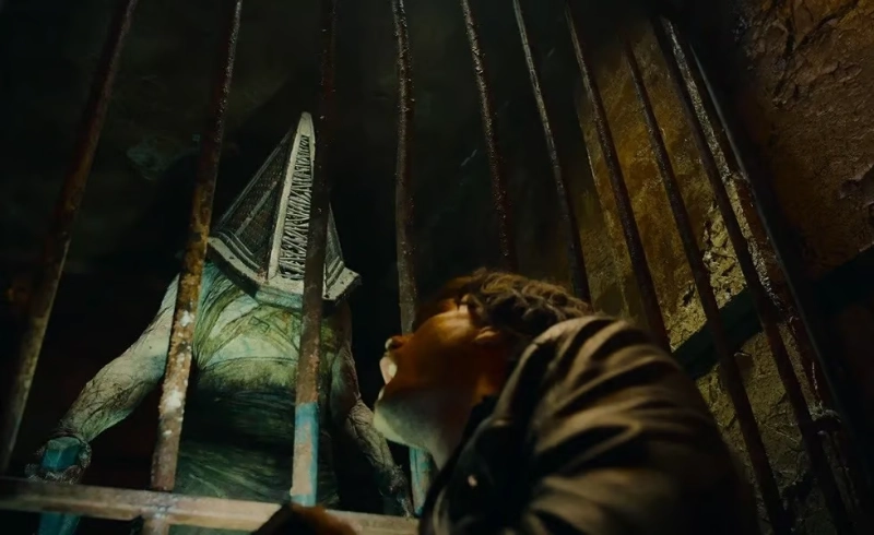 Pyramid Head towers behind bars as protagonist looks on in terror, Silent Hill adaptation, Image Credits - Konami Digital Entertainment