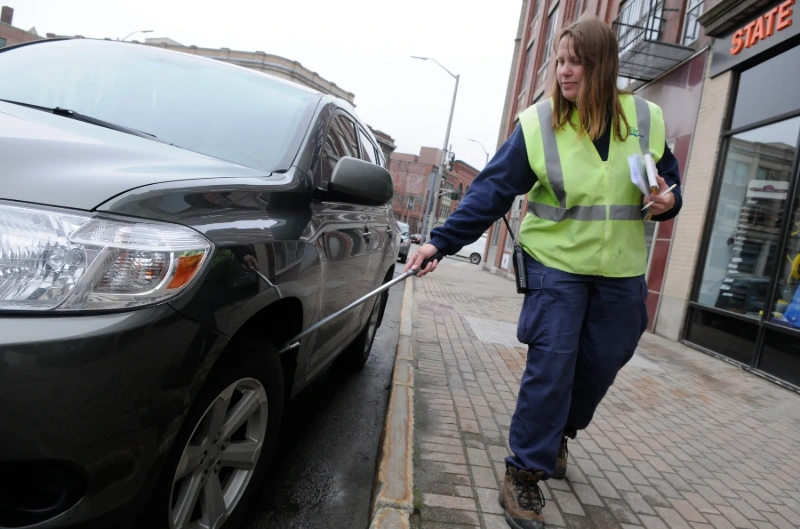 Bangor Police parking enforcement officer Marcia McGrath chalks tires on Harlow Street, credits John Clarke Russ