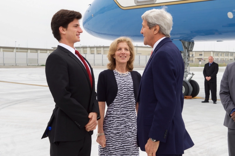 Jack Schlossberg and Kerry Kennedy converse with John Kerry on an airport tarmac, with Air Force One in background. Image Credits - U.S. Department of State photo / Public domain via Wikimedia Commons