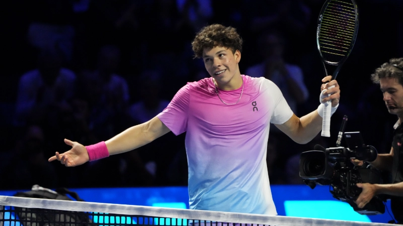 Ben Shelton raises his arms in victory, holding tennis racket at the net during the Swiss Indoors Basel 2024 ATP 500 event. Image Credits - Photo by Peter Arnold (Skyscraper2010), licensed under CC BY-SA 4.0 via Wikimedia Commons
