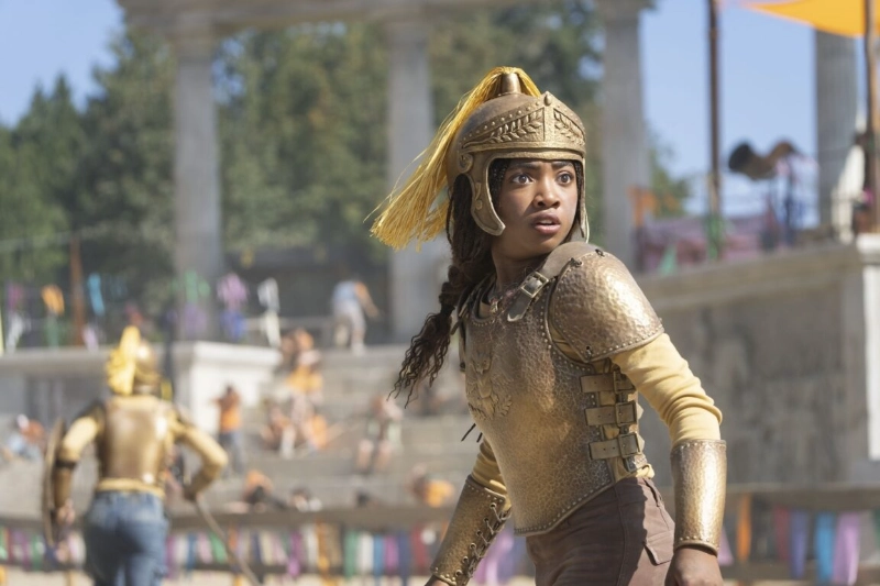 Annabeth Chase in golden Greek armor, training at Camp Half-Blood arena in Percy Jackson Disney+ series.