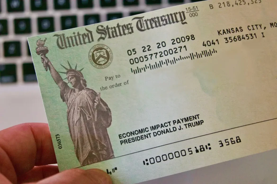 A hand holding an Economic Impact Payment check issued by the U.S. Treasury related to $1,400 Stimulus Checks.