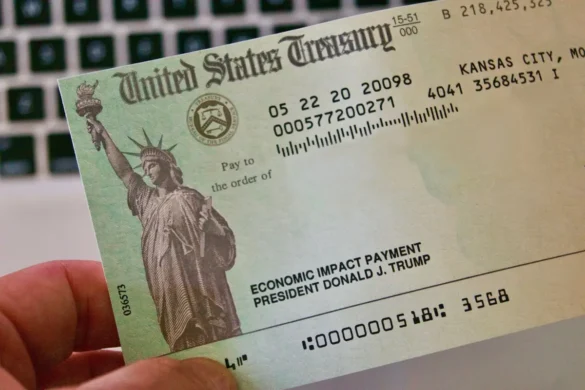 A hand holding an Economic Impact Payment check issued by the U.S. Treasury related to $1,400 Stimulus Checks.