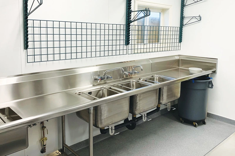 What is a deep sink: commercial triple-basin deep stainless steel sink in kitchen.