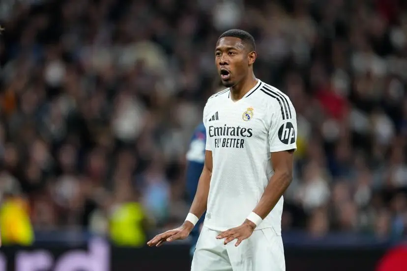 David Alaba soccer player in Real Madrid jersey with the logo and sponsor 'Emirates Fly Better,' on a soccer field with blurred spectators in the background. Image credit: David Alaba (Oscar J. Barroso/AFP/Presse Sports).