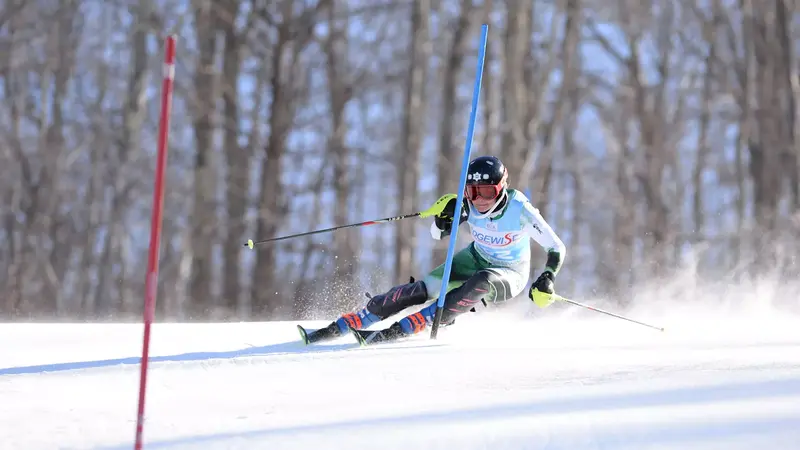 Ellery Curtis navigating a slalom course on a snowy slope, wearing a helmet and ski gear. Related to Ellery Curtis. Image Credits: Gil Talbot Photography.