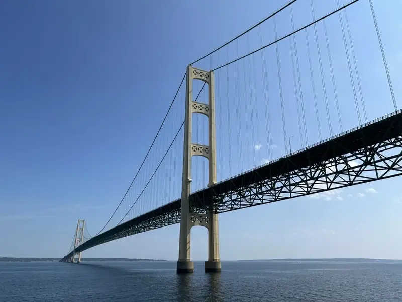 Mackinac Bridge - Large suspension bridge with tall towers and numerous cables, spanning across a body of water with a clear sky.