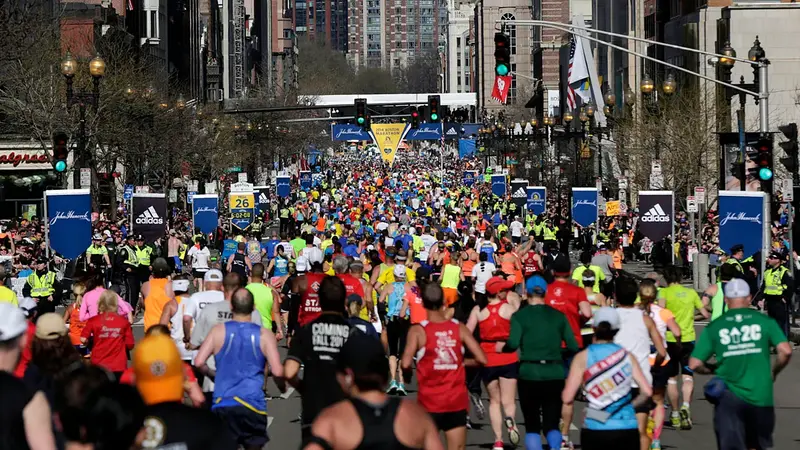 Runners approach Boston Marathon 2025 finish line, city backdrop.
