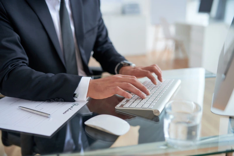 Business professional typing on a white keyboard at a glass desk, highlighting the March 2025 U.S. Jobs Report.