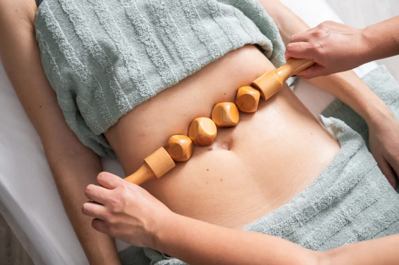 Benefits of Wood Therapy: wooden roller massage on abdomen for lymphatic drainage.