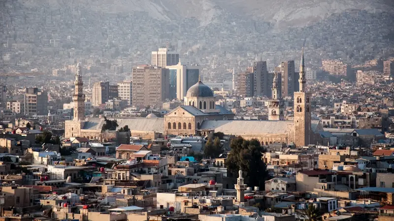 Syria in 2025: Umayyad Mosque and Damascus skyline with mountains.