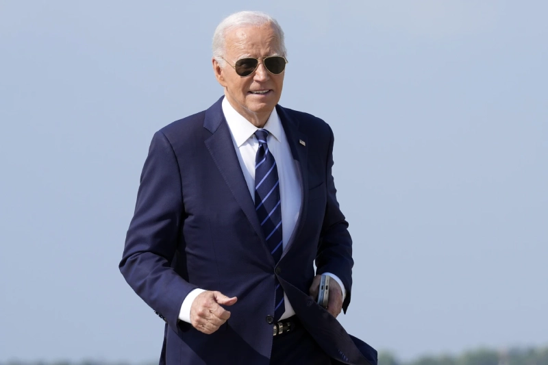 Joe Biden: walking outdoors in navy suit for official event.