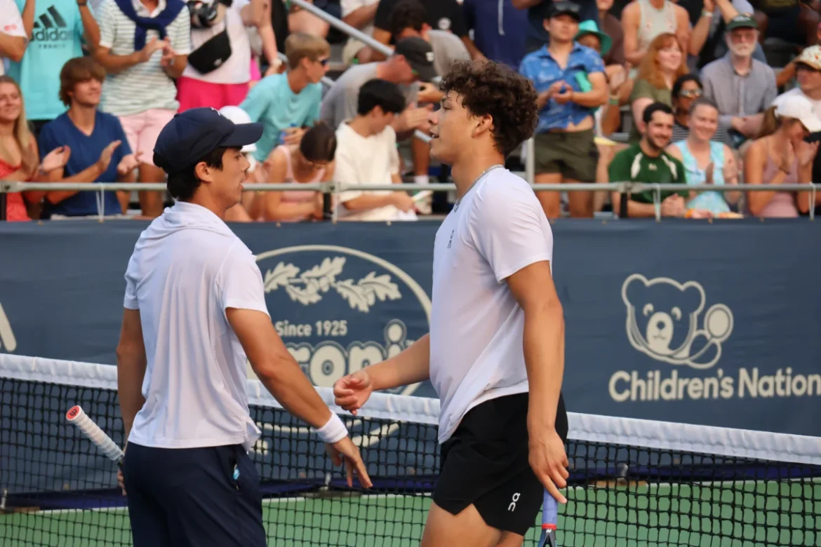 Ben Shelton (right) stands at the net with an opponent after a competitive tennis match, crowd applauding in the background. Image Credits - Photo by Hameltion, licensed under CC BY-SA 4.0 via Wikimedia Commons
