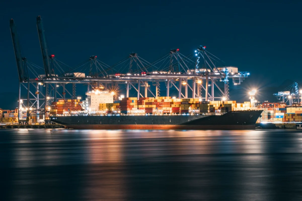 A container ship loaded with cargo under lit cranes at a port at night