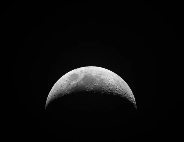 A thin crescent Moon in a dark night sky