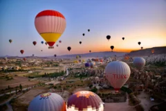 Hot air balloons rising at sunrise over the rock formations of Cappadocia, Türkiye