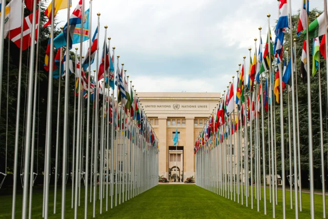 Two rows of national flags leading to the Palais des Nations, the United Nations building in Geneva